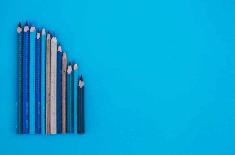 A mix of different sized pencils is laying on a blue surface