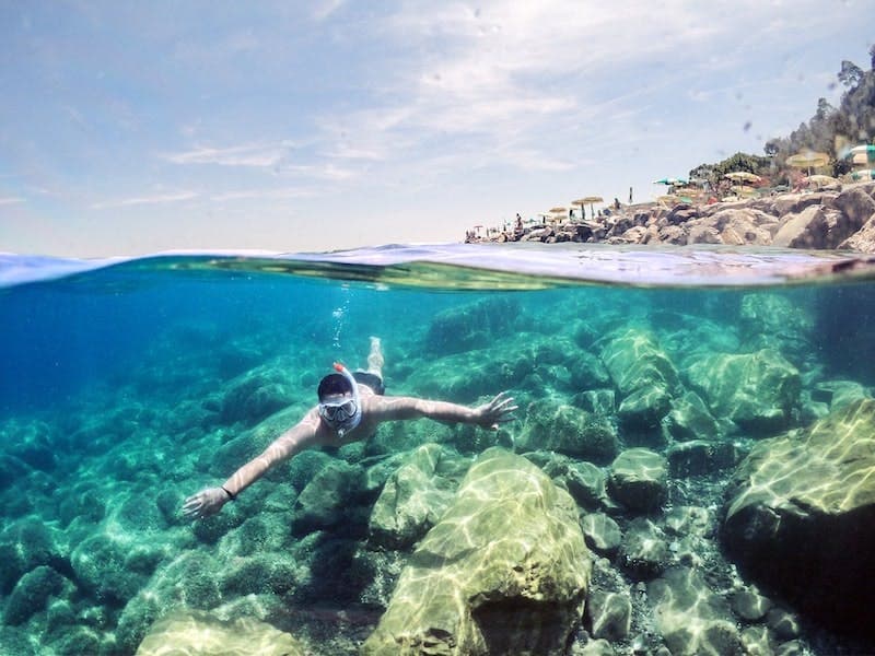A man is scuba diving in crystal clear waters