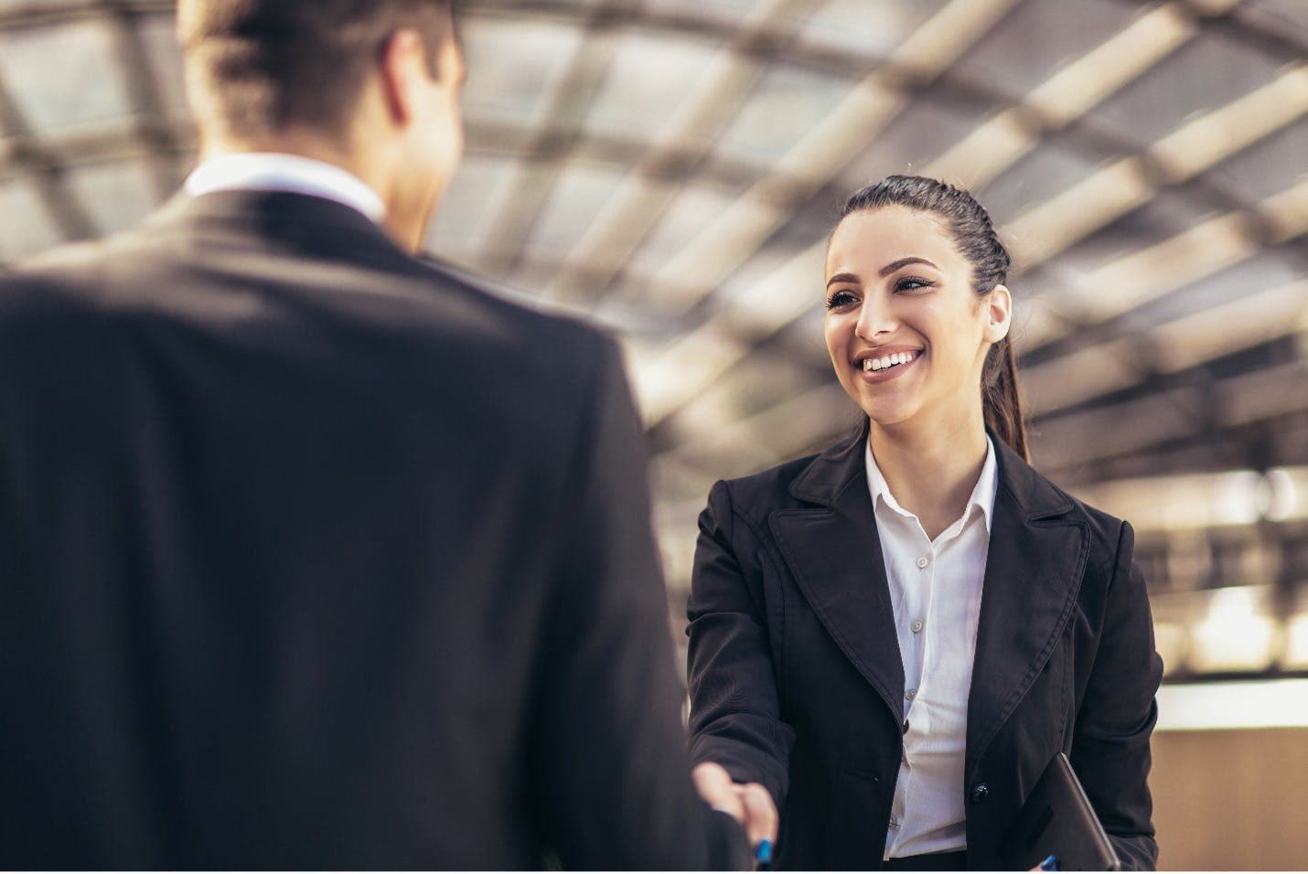 Two PR professionals shaking hands at a networking event.