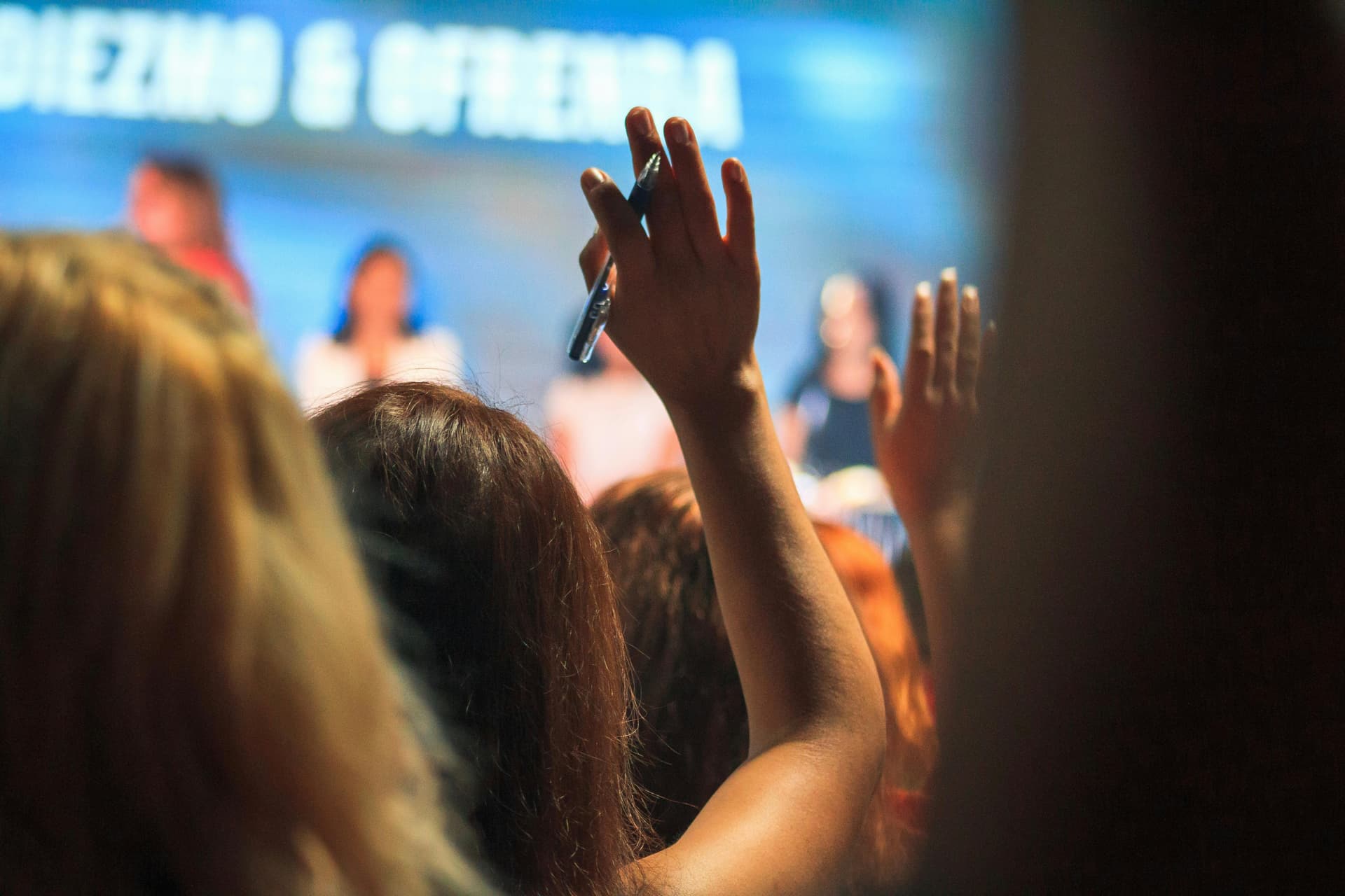 Woman at conference raising hand with a question