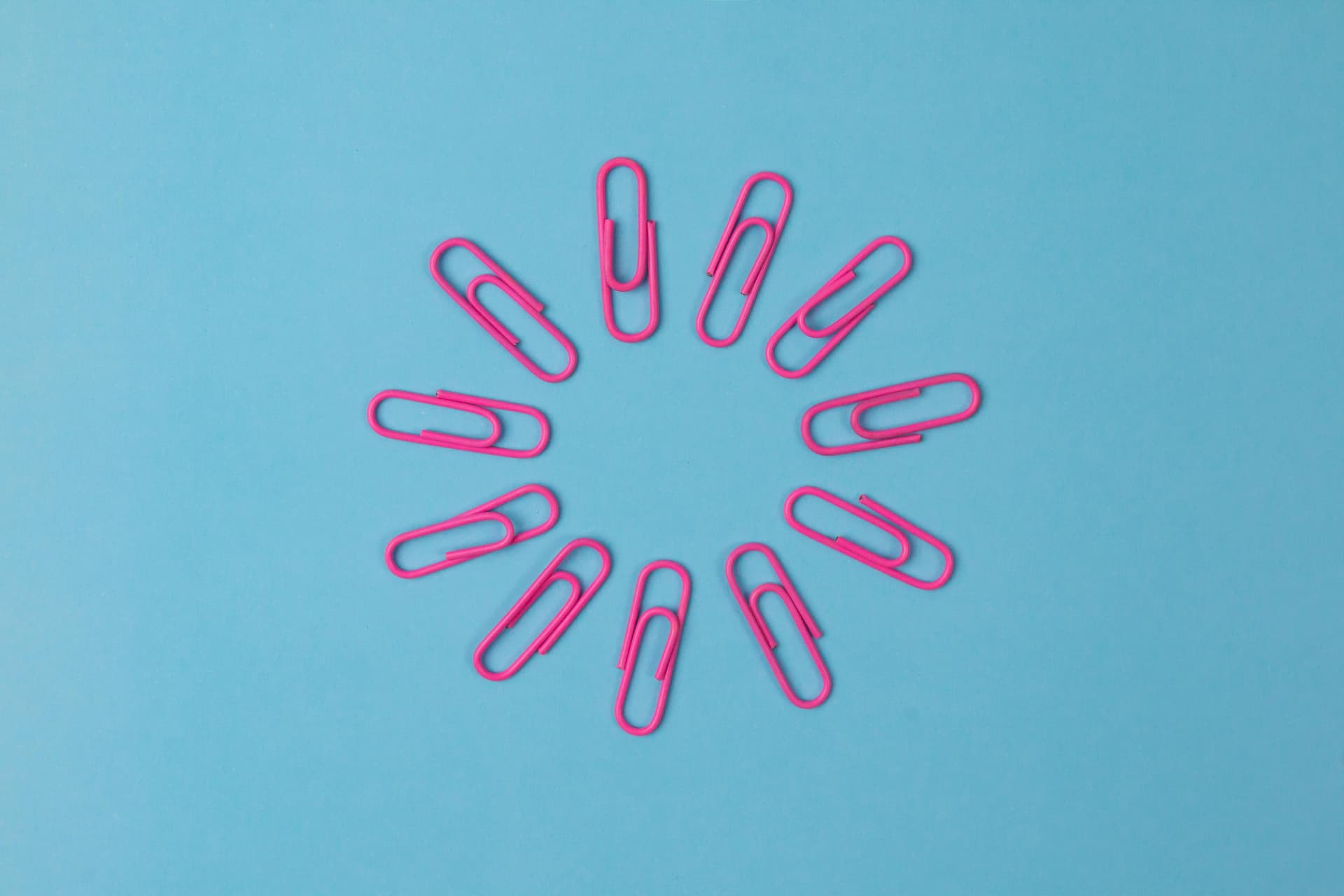 Circle of pink paper clips on a blue background. Don't get lazy with linking when writing a blog post 
