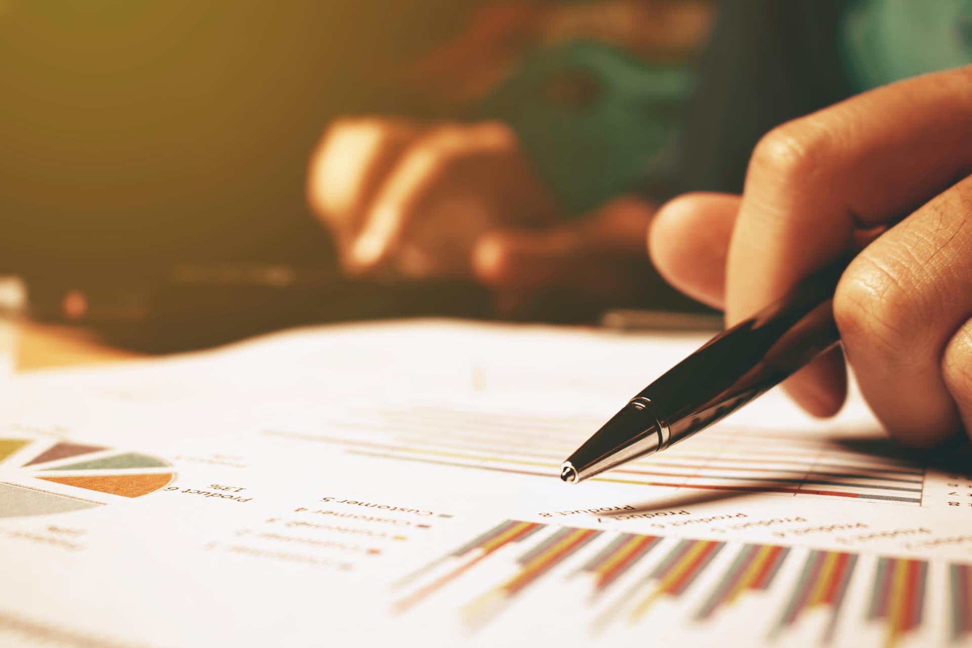 Close up of data graphs and person holding ball point pen, reporting PR pitch metrics and kpis