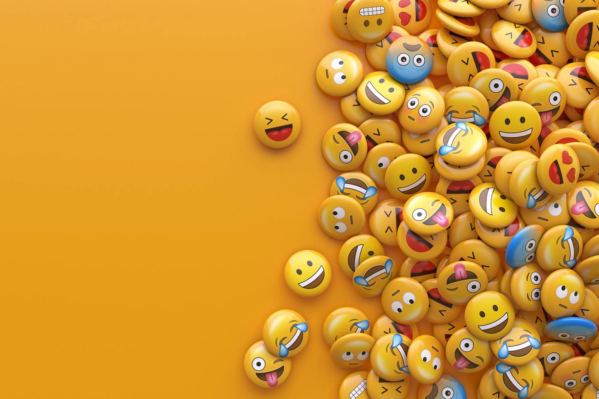 Une pile d'émojis sur un fond jaune uni. 