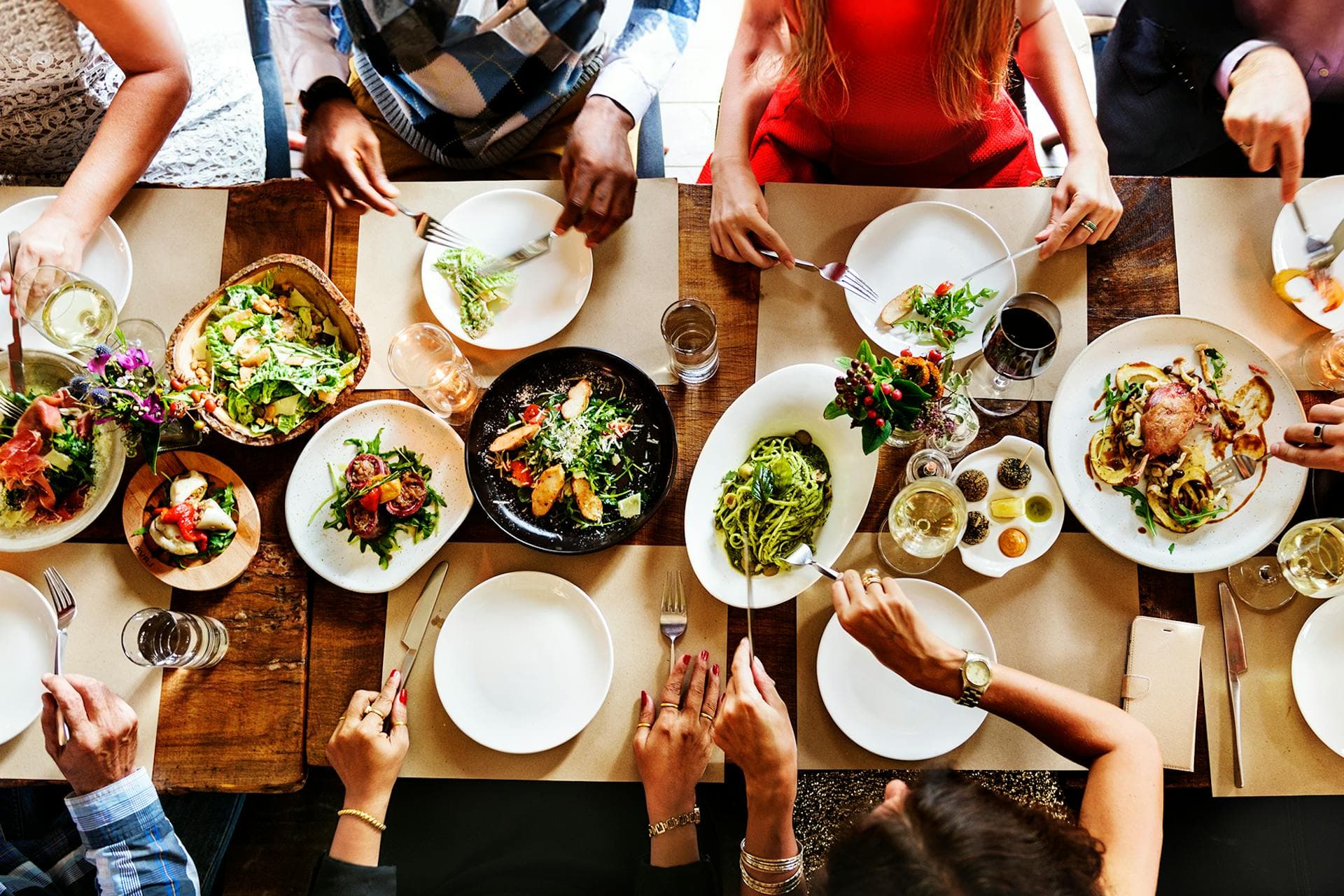 Des personnes assises à une table pleine d'assiettes de nourriture dans cette image pour le rapport 2024 Consumer Insights de Meltwater : Food & Beverage de Meltwater
